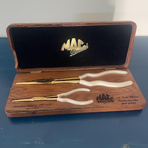 May include: A set of two 24k gold-plated needle-nose pliers with white handles, housed in a wooden display case. The case features the text MAC Limited, Limited Edition 93 1995, and 24k Gold Plated Serial Number 2467 of 9999.