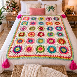 May include: A rectangular crochet blanket featuring a grid of multi-colored floral motifs in shades of pink, yellow, teal, and orange, joined by cream-colored yarn. The edges are finished with a colorful border and large pink tassels at each corner.