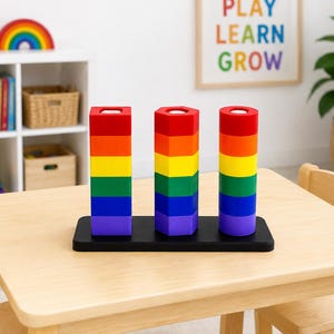May include: A wooden toy set featuring three vertical stacks of colorful blocks in red, orange, yellow, green, blue, and purple. The stacks are square, hexagonal, and cylindrical in shape, all mounted on a rectangular black base.