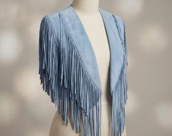 May include: A light blue suede vest featuring an open front design and long, cascading fringe detailing that extends from the shoulders down the front panels. The garment is sleeveless with a smooth texture and a clean, collarless neckline.