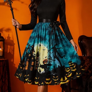 May include: A long-sleeved dress with a solid black bodice and a flared skirt featuring a vibrant Halloween print. The skirt displays a night scene with a large yellow moon, a haunted house, bare trees, and a border of glowing orange jack-o'-lanterns.