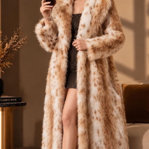 May include: A long, floor-length faux fur coat featuring a tan and white spotted animal print pattern, a wide collar, and long sleeves. The coat is worn over a dark, shimmering, sleeveless mini dress with thin straps and a straight neckline.