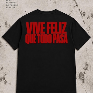 Può includere: Una t-shirt nera a maniche corte con il testo rosso VIVE FELIZ QUE TODO PASA stampato sul retro. La maglietta include del testo aggiuntivo in alto che riporta DROPWEAR MORE THAN A T-SHIRT, SAME ATTITUDE DIFFERENT STORIES e BLACK EVERYDAY STYLE ANYWHERE.