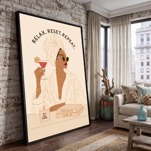May include: A framed wall art print featuring a line art illustration of a person in a towel wrap and robe, holding a cocktail. The text reads RELAX. RESET. REPEAT. at the top, with SELF CARE. ALWAYS. on a candle and FOCUS ON YOU GLOW UP on books.