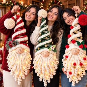 May include: Three handmade crochet gnome wall hangings with long white beards and integrated LED lights. One features red and white stripes with pinecones, one green and white with a flower, and one white with red pom-poms and gold bells.