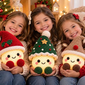 May include: Three round, illuminated crochet plush toys with smiling faces and rosy cheeks. One wears a red hat with holly, one a green hat with a yellow star, and one a brown hat with reindeer antlers. Each has a white pom-pom on the hat tip.