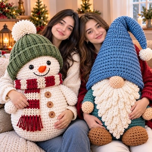 Puede incluir: Un muñeco de nieve de ganchillo grande con un gorro verde acanalado, un pompón blanco y una bufanda de rayas rojas y blancas con tres botones marrones, junto a un gnomo de ganchillo grande con un gorro azul alto y una barba blanca texturizada.