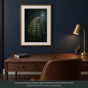 May include: A rectangular wall art print in a gold frame featuring a dark, moody botanical illustration of a green fern leaf next to a vertical wooden structure. The artwork is displayed on a dark blue wall above a wooden desk with a gold lamp.
