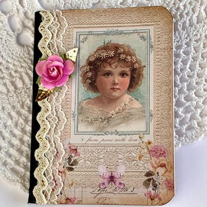 May include: A small, vintage-style journal with a floral design and a pink flower embellishment. The cover features a picture of a young girl with a flower crown and the text "from pans with love".