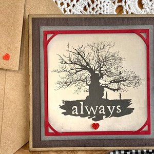 May include: A card with a red frame and a silhouette of a tree with two figures standing in front of it. The text "always" is printed on the card with a red heart.