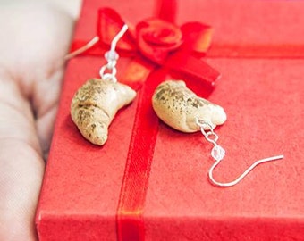 May include: A red gift box with a gold ribbon and a pair of croissant-shaped earrings. The earrings are made of polymer clay and have a gold finish.