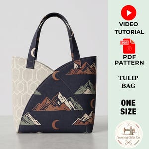 May include: A tote bag featuring a dark blue fabric with a mountain and crescent moon print, contrasted by a light beige side panel with a geometric hexagon pattern. The bag has two handles and text reading VIDEO TUTORIAL, PDF PATTERN, TULIP BAG, ONE SIZE.