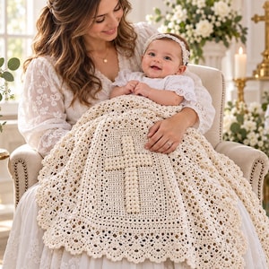 May include: A cream-colored crochet baby blanket featuring a central cross motif made of raised bobble stitches. The blanket has an intricate openwork pattern throughout and a wide, scalloped lace border along the entire outer edge.