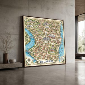 May include: A framed, illustrated map of Philadelphia featuring the Schuylkill and Delaware Rivers, City Hall, the Philadelphia Museum of Art, Eastern State Penitentiary, Reading Terminal Market, Elfreth's Alley, Liberty Bell, and Independence Hall.