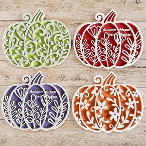 May include: Four decorative pumpkin-shaped cutouts featuring intricate white overlays. The top left is green with swirls, the top right is red with floral stems, the bottom left is purple with floral stems and text, and the bottom right is orange with flowers.