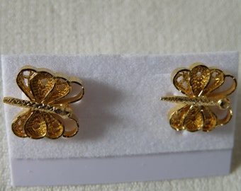 May include: A pair of gold butterfly earrings with intricate filigree designs. The earrings are displayed on a white card.