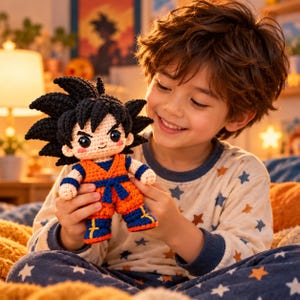 Könnte beinhalten: Eine handgefertigte Häkelpuppe eines Charakters mit stacheligem schwarzem Haar, die eine orangefarbene Kampfkunstuniform mit blauem Gürtel, blauen Armbändern und blauen Stiefeln mit gelben Akzenten sowie einem aufgestickten Lächeln trägt.