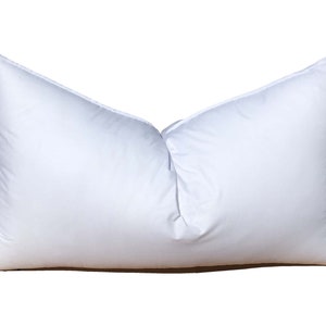 May include: A white rectangular pillow with a soft, fluffy appearance. The pillow is filled and has a smooth, clean surface. The pillow is designed for comfort and support, suitable for sleeping or decorative use.