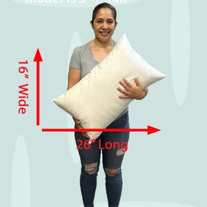 Lady holding an 16x26 pillow insert to demonstrate the size of the pillow form and how do I correctly measure my sham.  What size insert does an 15x25 lumbar sham need?  16 by 26 pillow inserts best fits a 16 by 24 decorative pillow sham.  What size pillow does my decorative sham need.  What size pillow insert does my 15 by 26 travel pillow cover need?
