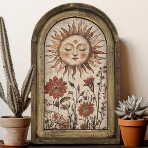 May include: A wooden framed wall art piece with a painted image of a sun with a face and flowers. The sun is yellow with a red and brown face and the flowers are red and brown. The frame is a dark brown wood with a light brown background.