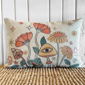 May include: A decorative pillow with a beige background featuring a whimsical design of orange, yellow, and green flowers, mushrooms, and stars.