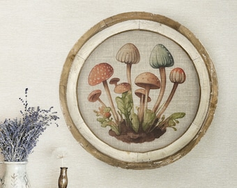 Könnte beinhalten: Ein runder Holzrahmen mit weißem Leinenhintergrund, der ein Aquarellbild von bunten Pilzen zeigt. Der Rahmen hängt an einer hellbeigen Wand über einer Kommode aus Holz mit zwei Schubladen.