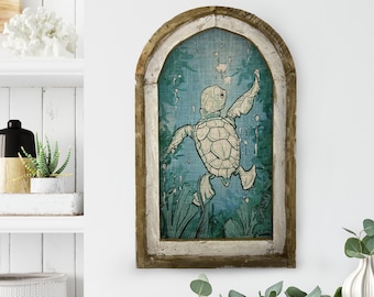 May include: A wooden framed wall art piece with a blue and green background featuring a white turtle swimming in the water. The turtle is depicted with its flippers outstretched and its head turned to the side. The frame has a distressed white paint finish.