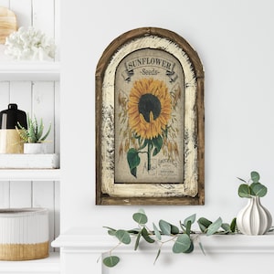 May include: A rustic wooden framed wall decor featuring a vintage sunflower seed packet illustration with the text "SUNFLOWER -Seeds- A. Moll Grocer Co. Grocers, Sioux City, Iowa".