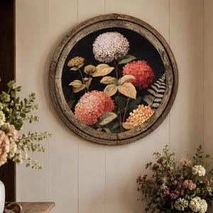 May include: A circular wall art piece featuring a botanical illustration of hydrangea flowers in shades of white, pink, and orange against a dark background, encased in a weathered, round wooden frame with a visible grain and textured finish.