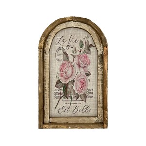 Pu&ograve; includere: Un decoro da parete in legno rustico con uno sfondo in lino che presenta un motivo floreale di rose rosa e il testo "La Vie Est Belle".