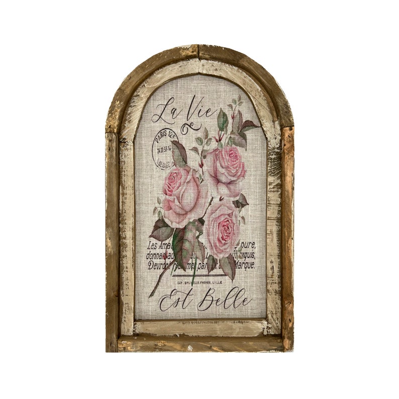 Pu&ograve; includere: Un decoro da parete in legno rustico con uno sfondo in lino che presenta un motivo floreale di rose rosa e il testo "La Vie Est Belle".