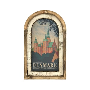 May include: A framed print of a castle with a white and brown wooden frame. The print features a castle with red and green accents and the text "Rosenborg Castle, Denmark, Romance of the Middle Ages".