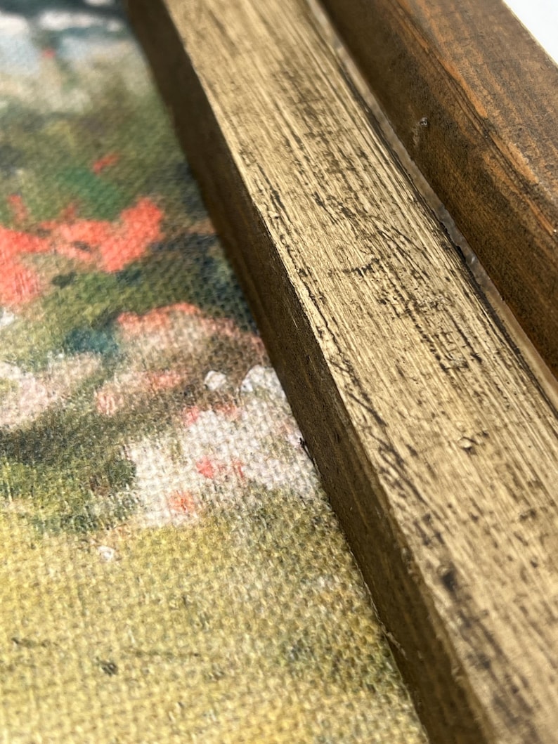 May include: Close-up of a framed painting with a gold-painted wooden frame. The artwork features a colorful, impressionistic landscape with red, green, and white hues. The frame has visible wood grain and a distressed finish.