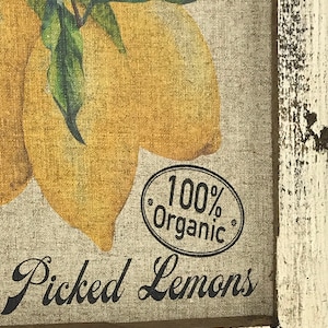 May include: A framed print of lemons with green leaves and white flowers. The print has a rustic, distressed look and says "100% Organic" and "Picked Lemons".