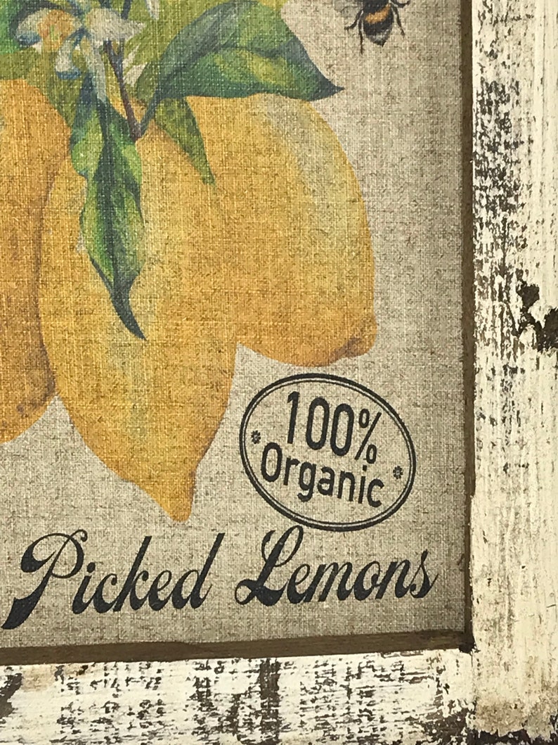 May include: A framed print of lemons with green leaves and white flowers. The print has a rustic, distressed look and says "100% Organic" and "Picked Lemons".