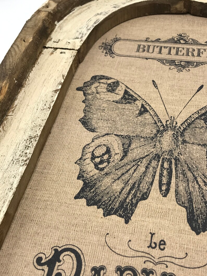 May include: A framed burlap canvas with a black and white butterfly illustration. The canvas has the text "Butterfly" and "Le Papillon" printed on it.