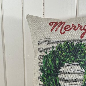 May include: A cream-colored pillow with a green wreath and the text "Merry" in red.