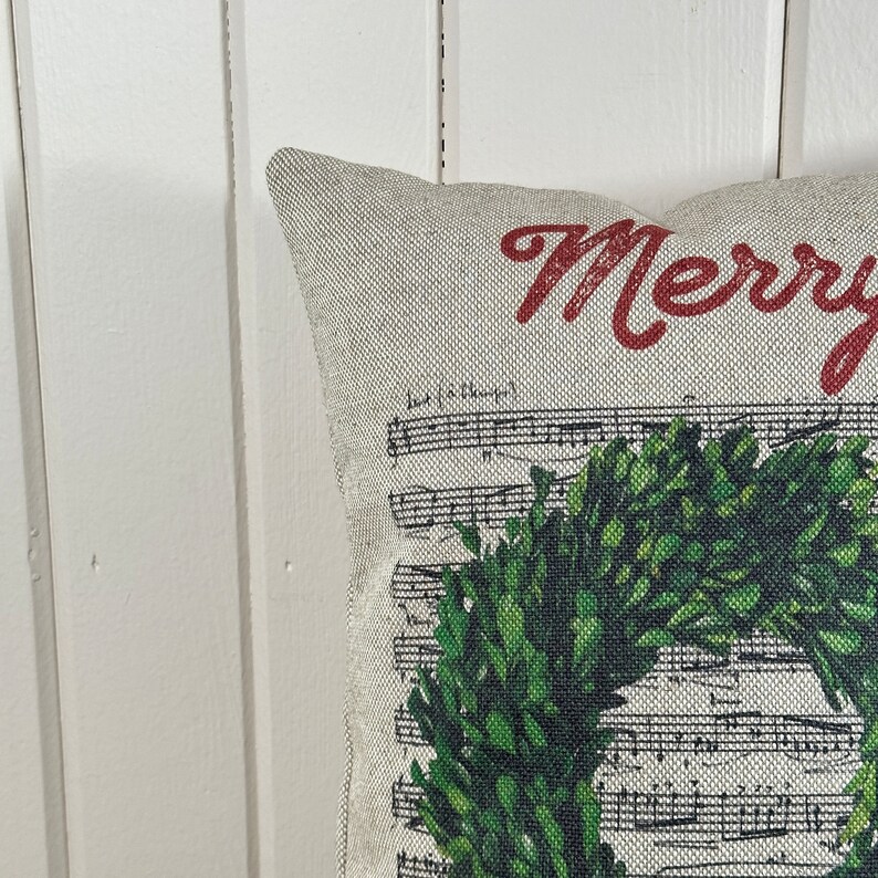 May include: A cream-colored pillow with a green wreath and the text "Merry" in red.