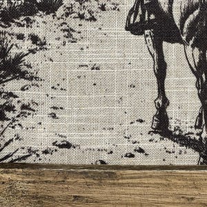 Puede incluir: Una imagen en blanco y negro de un caballo y un jinete impresa en un lienzo de arpillera. El lienzo est&aacute; enmarcado con un marco de madera marr&oacute;n oscuro.