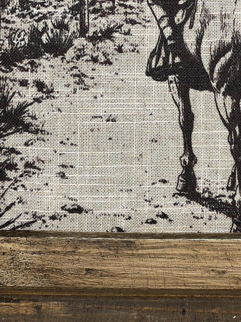 Puede incluir: Una imagen en blanco y negro de un caballo y un jinete impresa en un lienzo de arpillera. El lienzo est&aacute; enmarcado con un marco de madera marr&oacute;n oscuro.