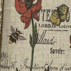 May include: A vintage-style print featuring a red poppy flower, a bee, and a butterfly. The print has a linen texture and includes the text "L'Atelier de L'Orris" and "Savoir".