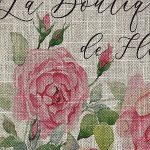 May include: A burlap fabric background with a floral design featuring pink roses and green leaves. The text "La Boutique de Fleurs" is written in black cursive script.