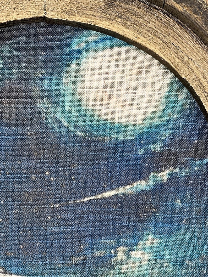 May include: A close-up of a blue and white abstract painting on a textured canvas. The painting features a large white circle surrounded by blue and white brushstrokes.