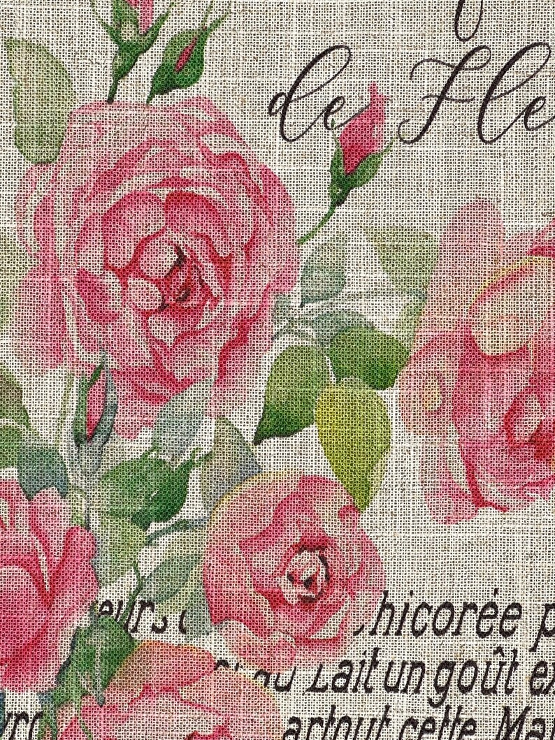 May include: A burlap fabric background with a floral design featuring pink roses and green leaves. The text "Le Fleurs" is written in black cursive script. The text "chicoree" and "au Lait un gout" is also visible.