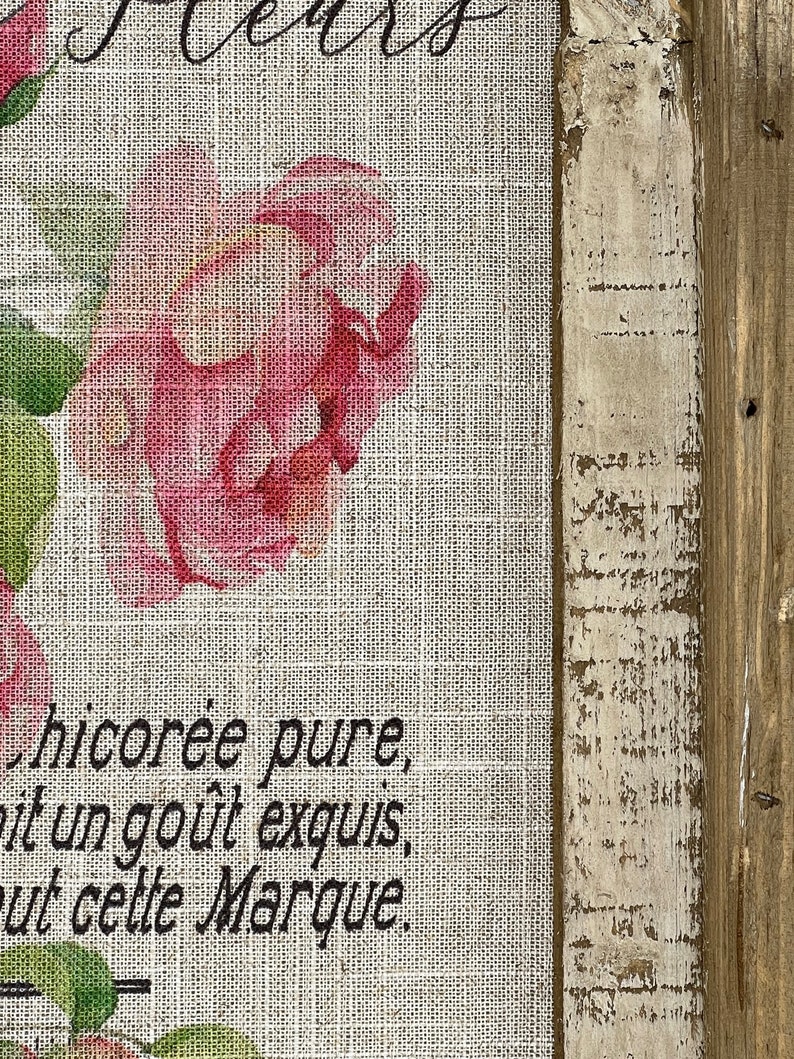May include: A burlap fabric with a pink rose and green leaves printed on it. The fabric has the text "chicor&eacute;e pure,  it un go&ucirc;t exquis,  ut cette Marque." printed on it.
