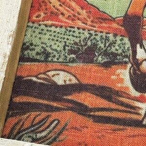 May include: A framed piece of art with a red, green, and brown design. The art is printed on a textured fabric.