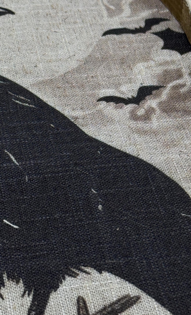 May include: A black crow silhouette on a beige burlap background with black bat silhouettes flying above.