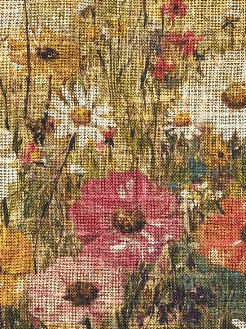 Puede incluir: Primer plano de una tela floral con textura de arpillera. La tela presenta una variedad de flores en tonos de rosa, amarillo y blanco, con hojas y tallos verdes.