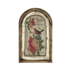 May include: A framed vintage-style print with a distressed white background and a brown wood frame. The print features a floral design with pink and white roses and a small red bird with a black beak and black eyes. The text on the print reads "Mme Boileve, rue Bourdon, 28, CHATELLERAULT, Paris, Fleurs".