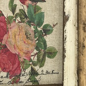 May include: A framed print with a vintage aesthetic featuring a bird perched on a branch with roses. The print has a distressed white frame and the text "La Musique est l'&acirc;me de l'univers" is visible in the bottom right corner.
